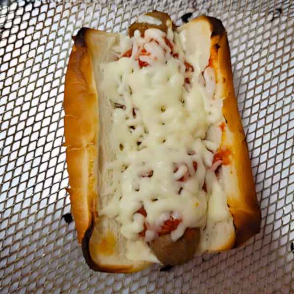 Momo's Pizzeria meatball sub with melted mozzarella cheese and marinara sauce on a metal rack.