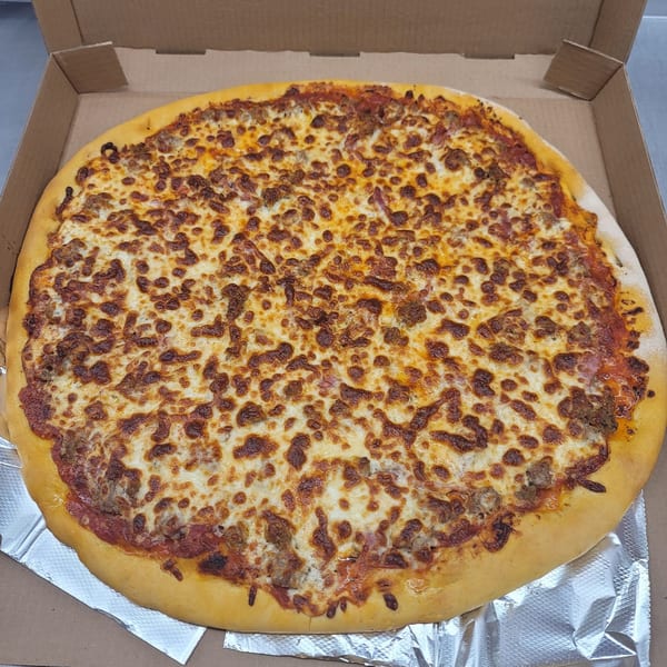 A freshly baked Momo's Pizzeria pizza with melted cheese and sausage in a cardboard box.