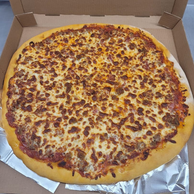 A freshly baked Momo's Pizzeria pizza with melted cheese and sausage in a cardboard box.