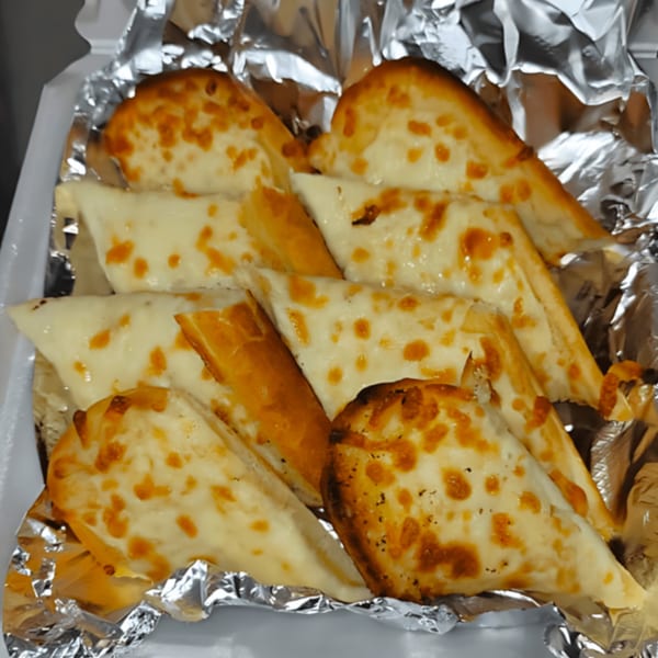 Cheesy garlic breadsticks from Momo's Pizzeria, golden brown and served in a foil-lined container.